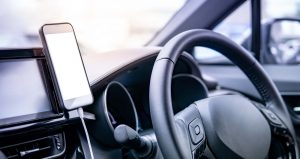 Smartphone with white blank screen mounting with magnet on the car console near steering wheel.